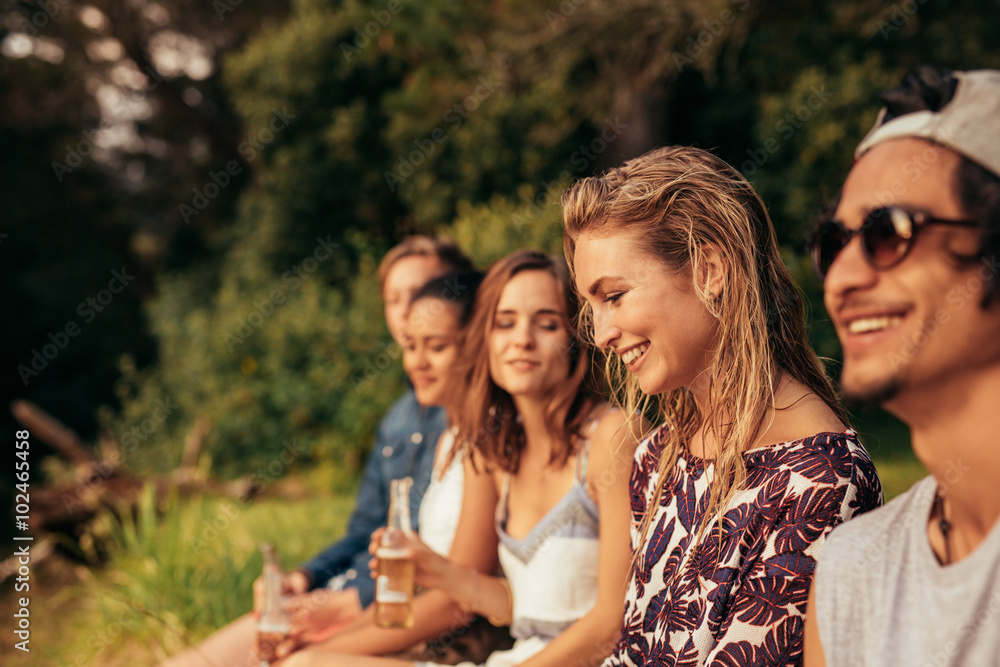 快乐的年轻女人和她的朋友坐在湖边