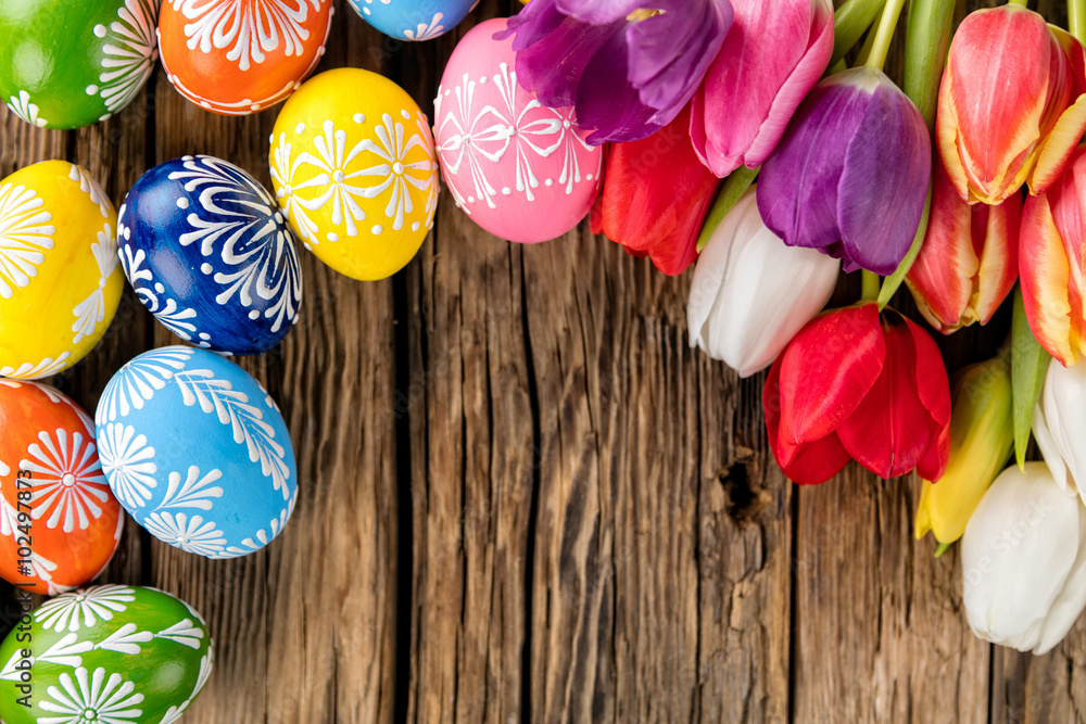木制背景上的复活节彩蛋和郁金香