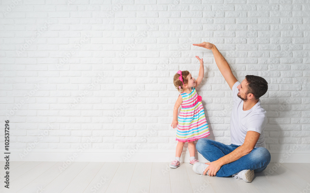 concept. Dad measures growth of her child daughter at a wall