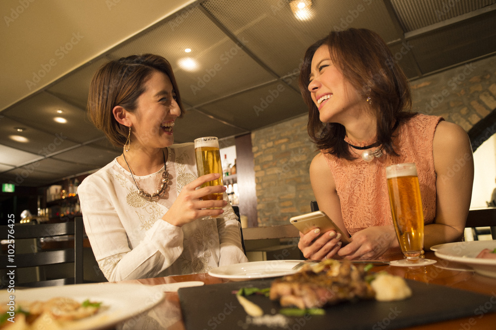 两个女人一边喝啤酒一边在餐厅用餐
