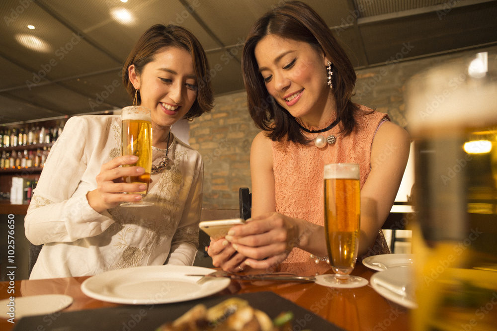 两个女人一边喝啤酒一边在餐厅用餐