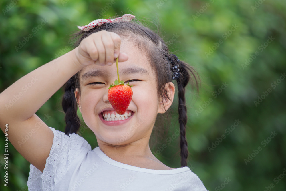女孩在浆果草地上吃草莓
