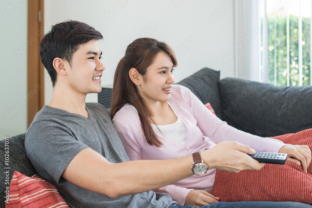 年轻的亚洲夫妇在家里看电视电影