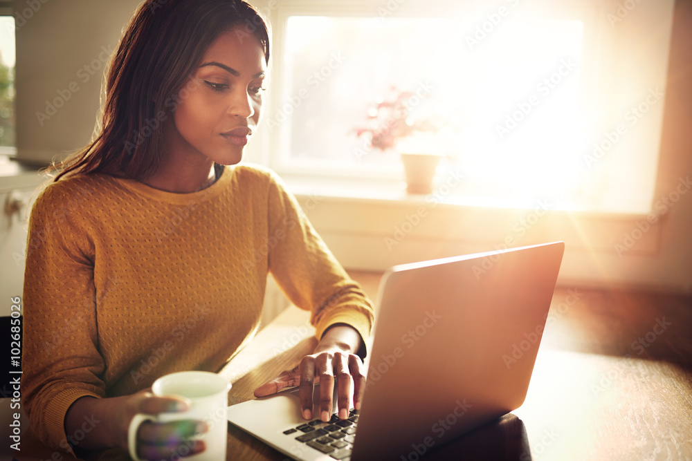 Woman checking her computer and holding coffee cup