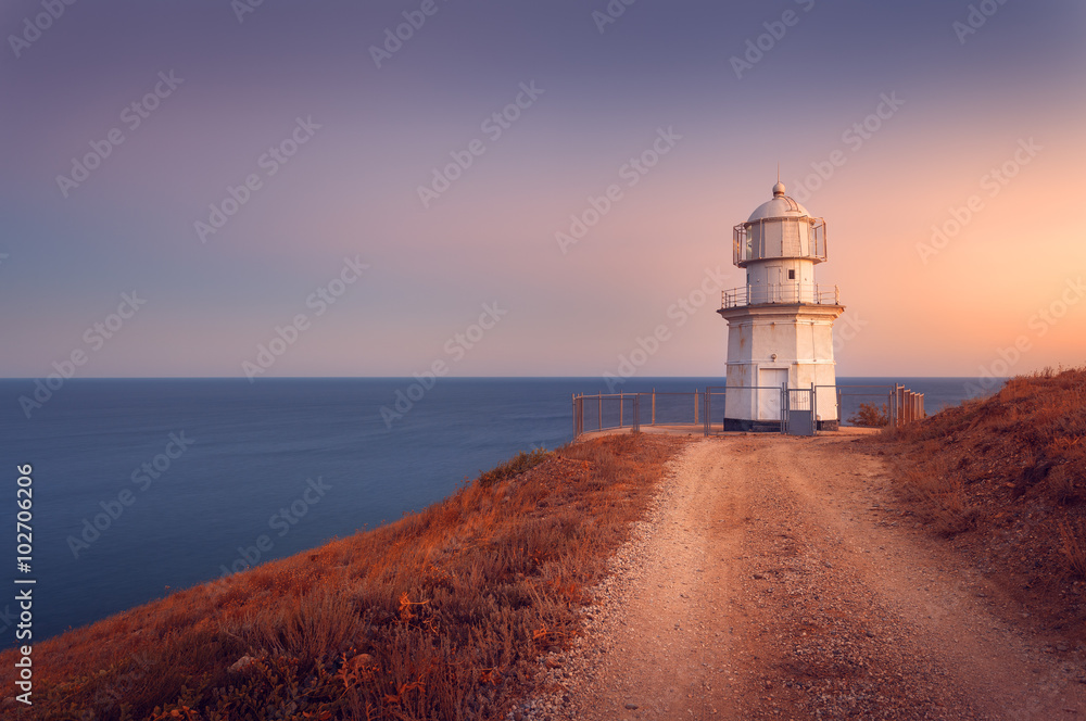 日落时海岸线上美丽的白色灯塔。兰