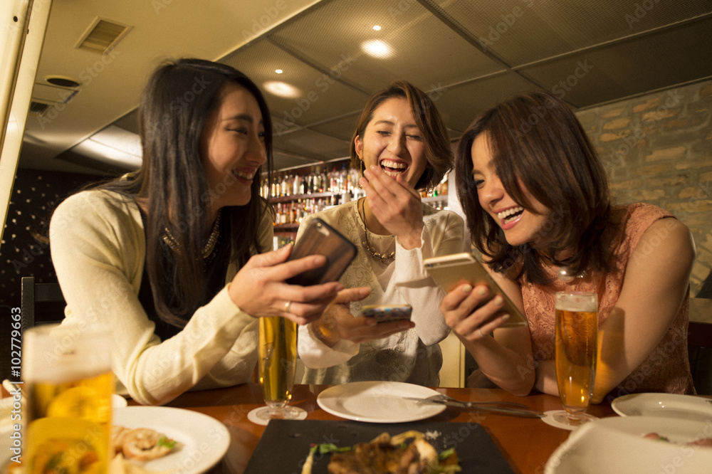 Three women are laughing while looking at the smartphone