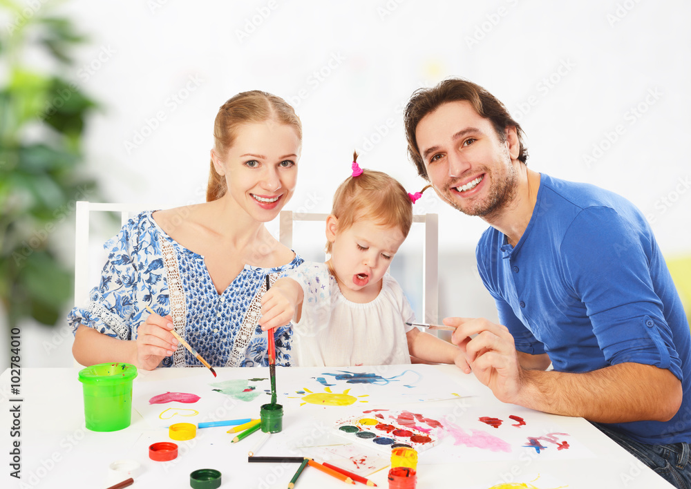 happy family: mother, father and child daughter draw paints