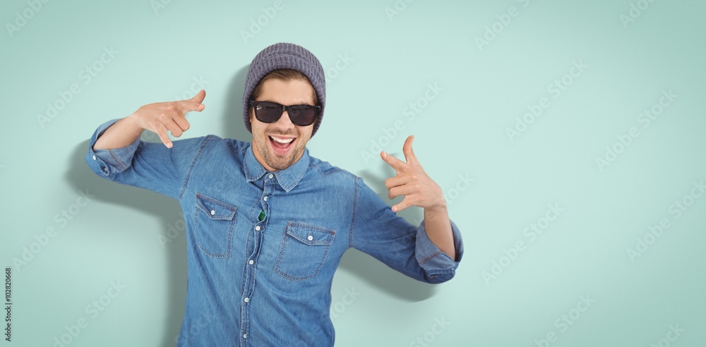 Composite image of happy hipster showing rock and roll hand sign