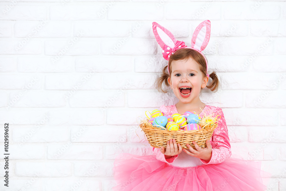 快乐的小女孩在服装复活节兔子与篮子