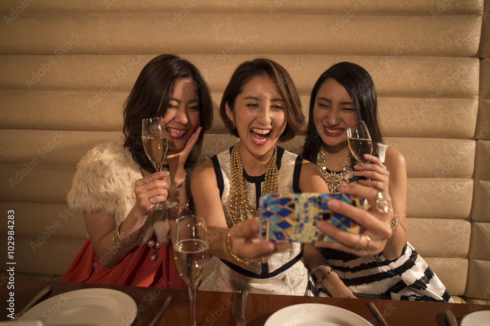 三名女性拿着香槟喝上了智能手机