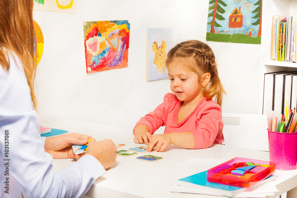 小女孩在课堂上从桌子上拿卡片