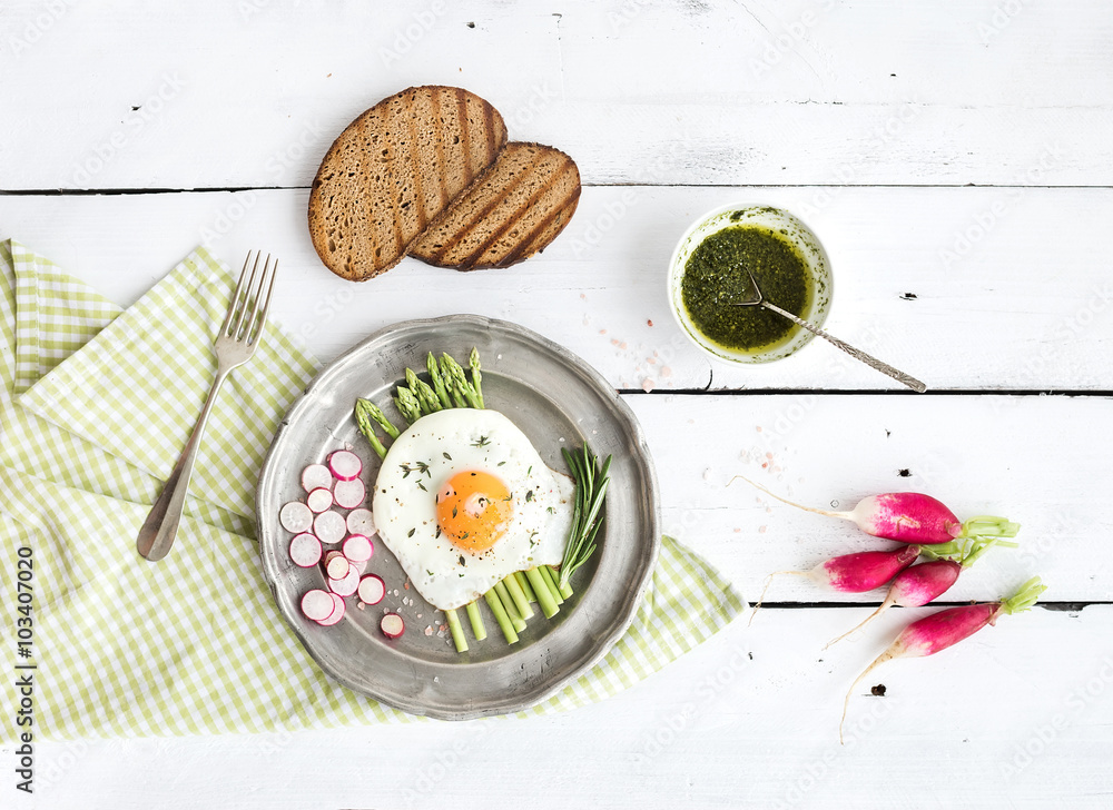 Healthy breakfast set. Fried egg with asparagus, radishes, green sauce and bread on vintage metal pl