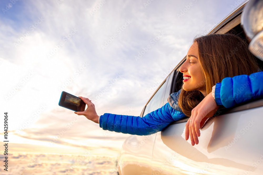 年轻女子用智能手机拍摄窗外美丽的云景