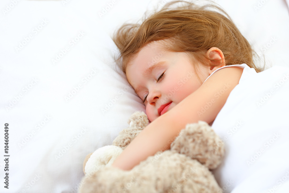 小女孩抱着泰迪熊睡在床上