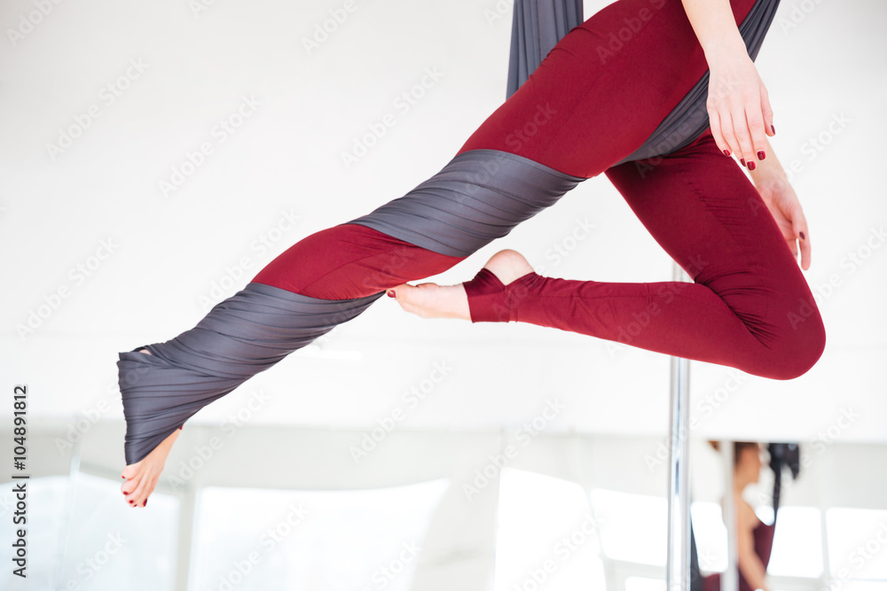 年轻女子穿着紧身裤在工作室练习空中瑜伽