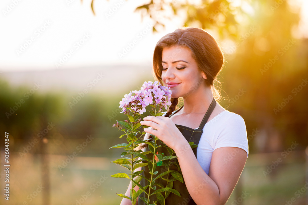 Young gardener in her garden smelling flowers, sunny nature