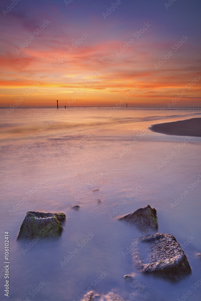 Beach with rocks at sunset in Zeeland, The Netherlands