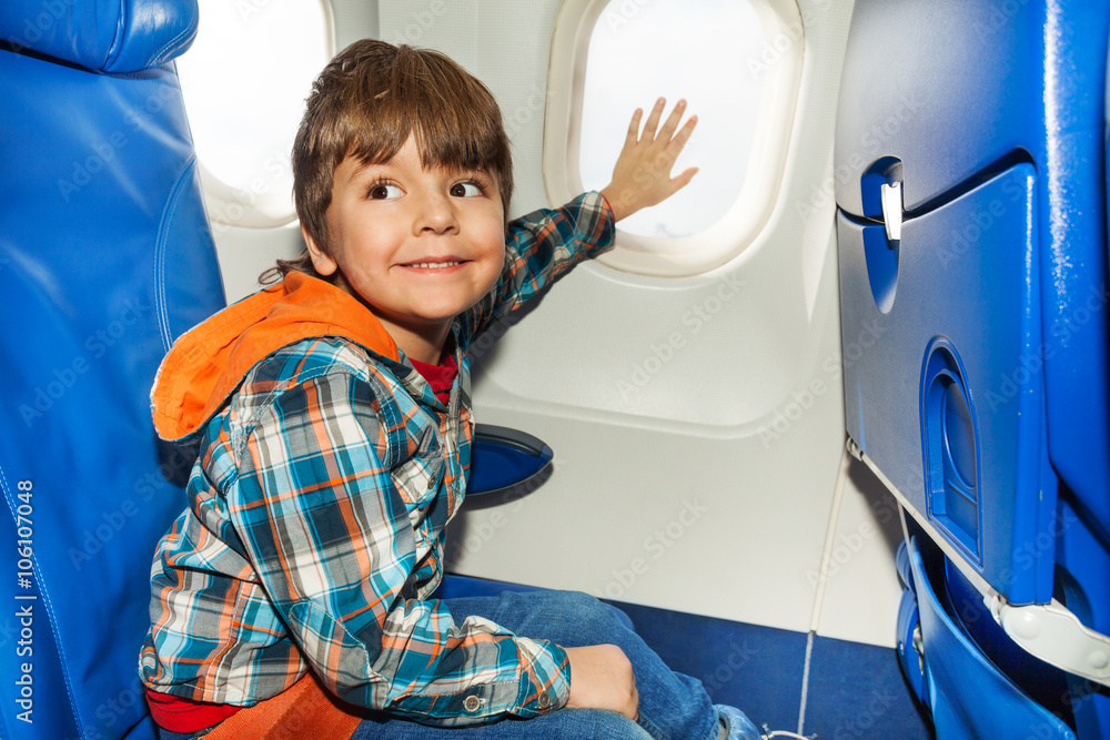 Child on airplane touch window with hand