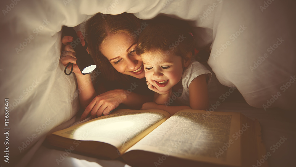 Family reading bedtime. Mom and child reading book with a flashl