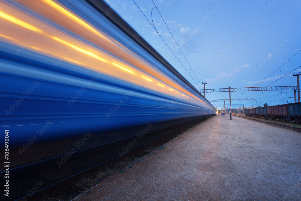 High speed passenger train on tracks in motion. Railway station