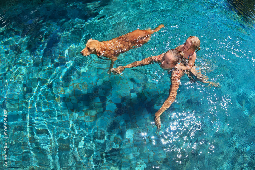 Mother with little child on back play with fun and train golden labrador retriever puppy in swimming