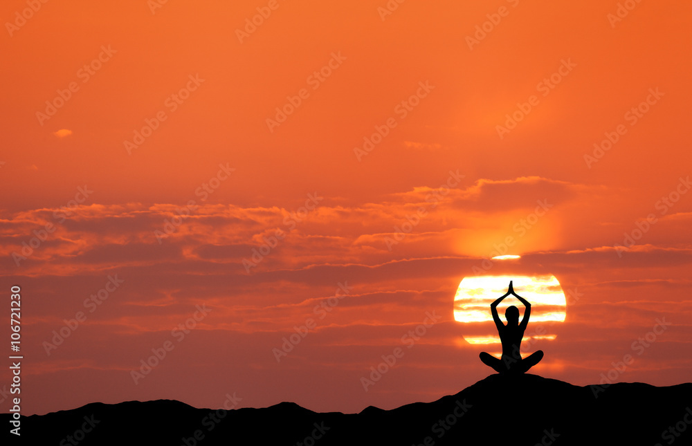 Sunset landscape with girl practicing yoga on the background of sun and red sky in the hill in summe