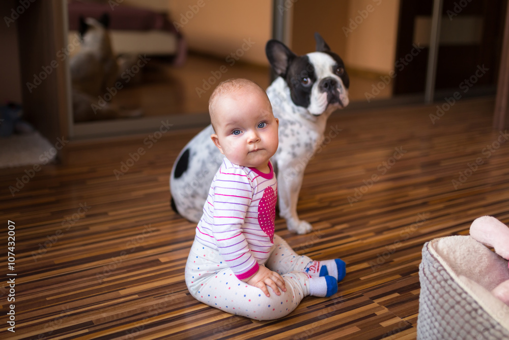 Little baby girl on the floor with french bulldog friend