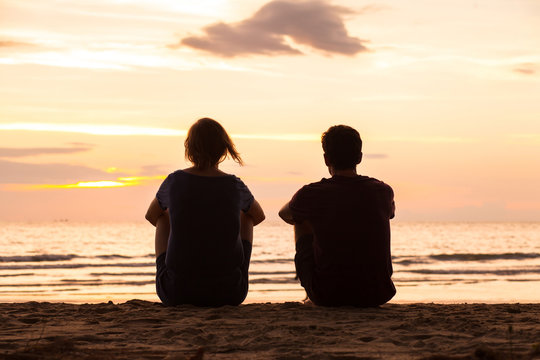 朋友们一起坐在海滩上看日落，友谊观