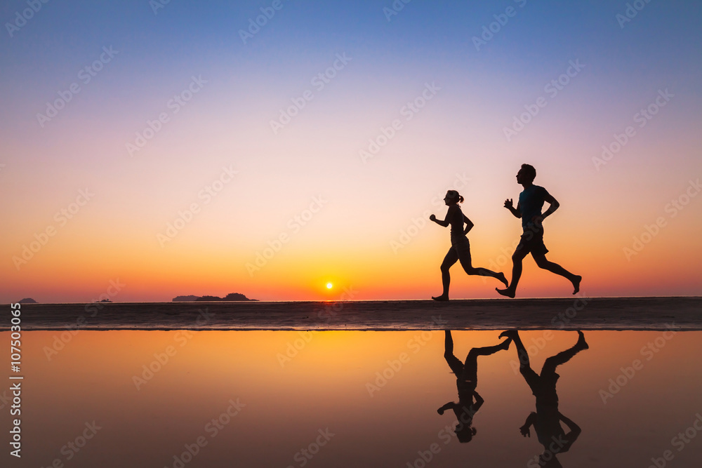 锻炼，日落时海滩上两名跑步者的剪影，运动和健康的生活方式背景