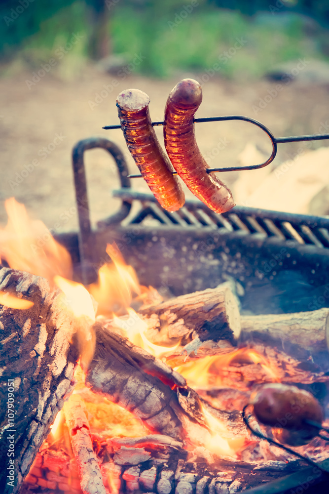 Preparing sausages on campfire 