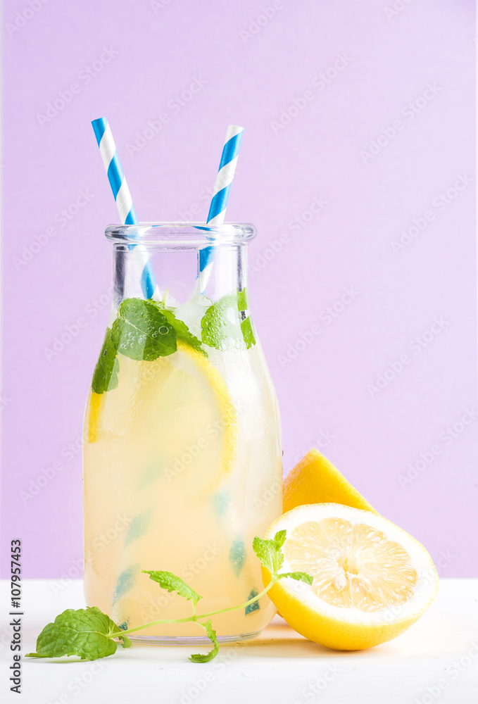 一瓶自制柠檬水，配薄荷、冰块、柠檬、纸吸管和淡紫色背景
