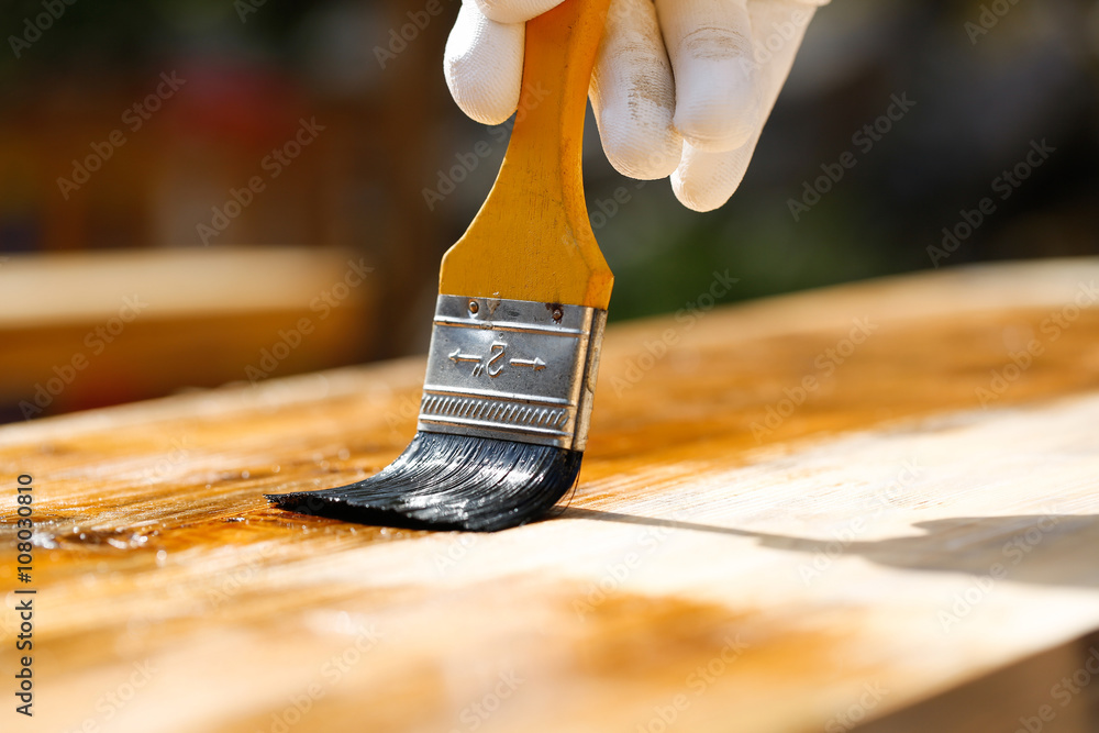 油漆工在木质表面喷漆，保护木材