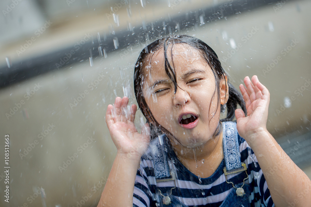 Asian girl playing with water fountain at water park