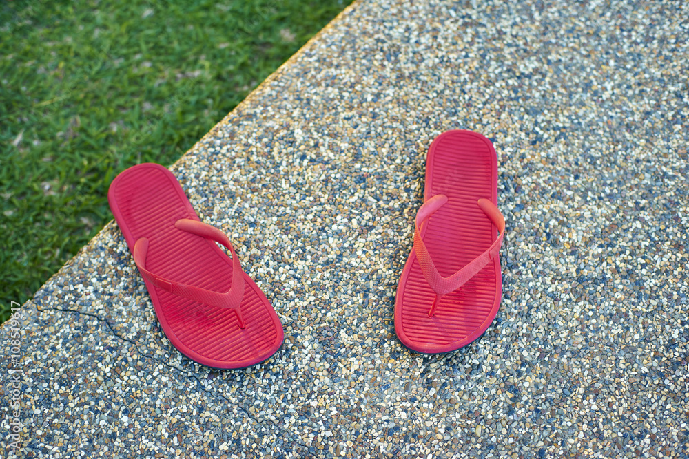 放置在石头地板上的一双红色舒适拖鞋