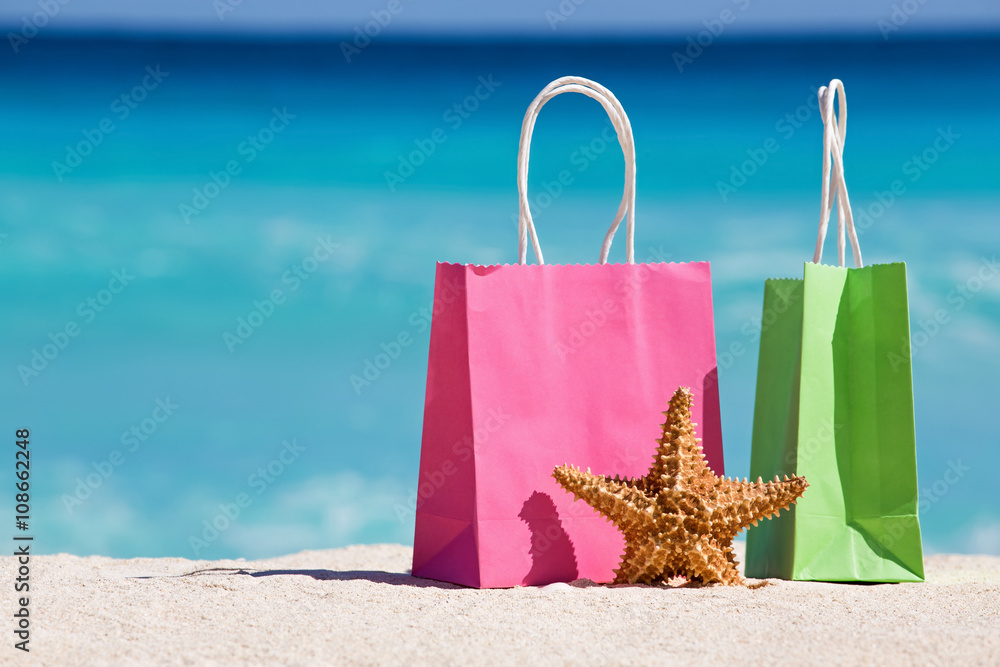 购物袋和沙滩上的海星对抗绿松石加勒比海