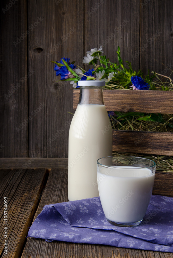 木桌上的一瓶乡村牛奶和一杯牛奶