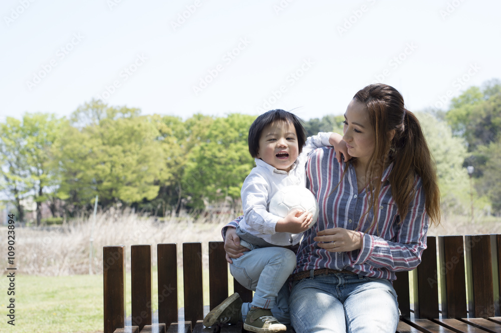 Mother and son sitting on a bench in the park