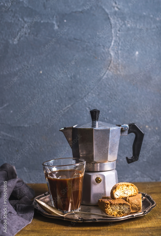 Glass espresso coffee on rustic wooden board, cantucci biscuits and steel Italian Moka pot, grey bac