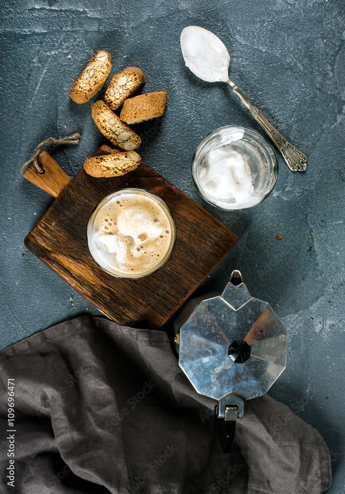 Glasses of coffee with ice cream on rustic wooden board, steel Italian Moka pot over grey concrete t