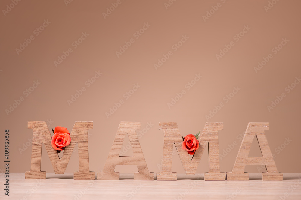 柔和背景上有粉色玫瑰花的MAMA字母块。母亲节快乐概念。