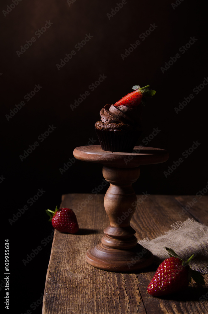 木桌上的草莓巧克力纸杯蛋糕。