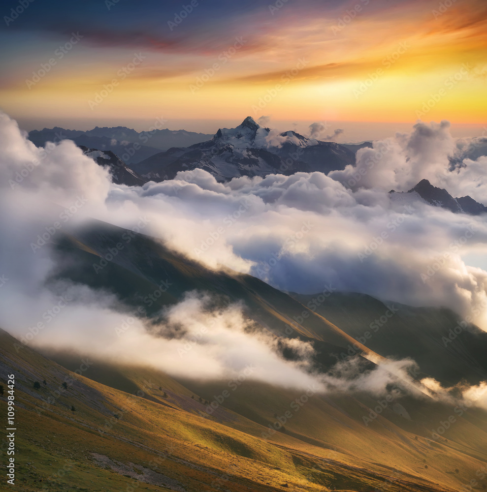 High mountain ridge in the clouds during sunrise. Beautiful panoramic landscape