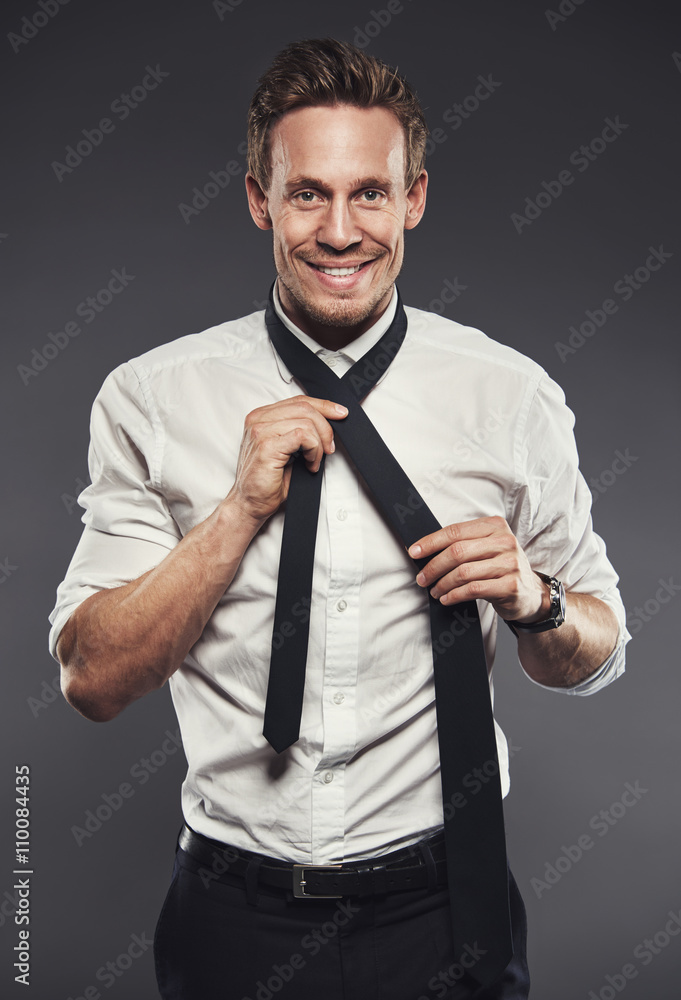 Smiling businessman tying his necktie