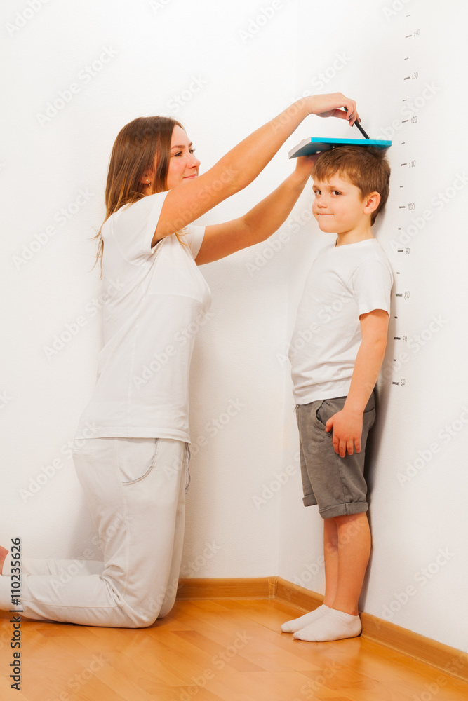 母亲靠墙测量儿子的身高
