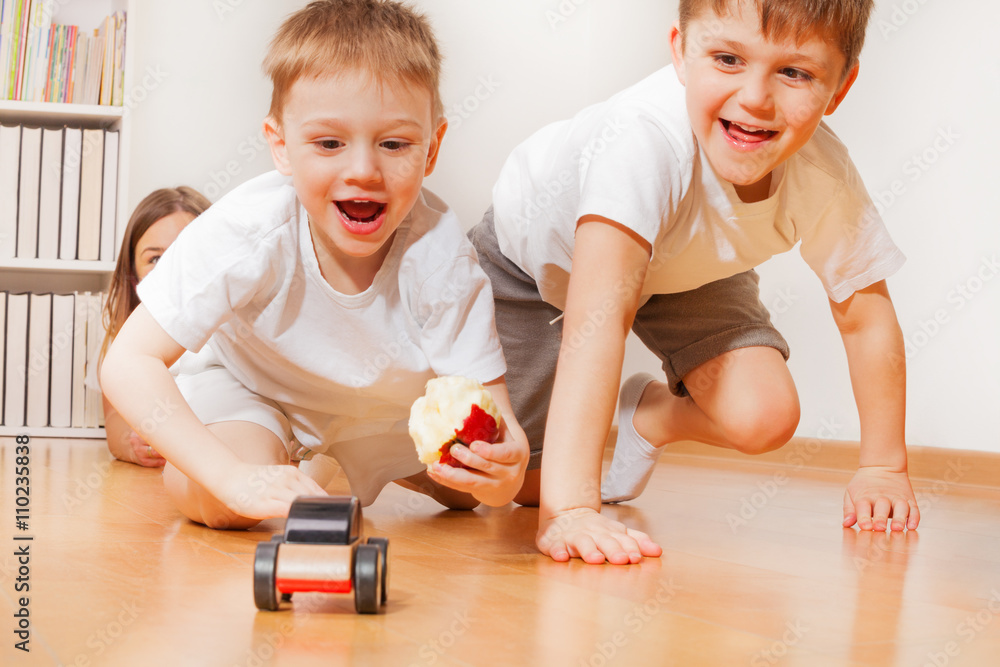 快乐的孩子们在地板上玩木制玩具车