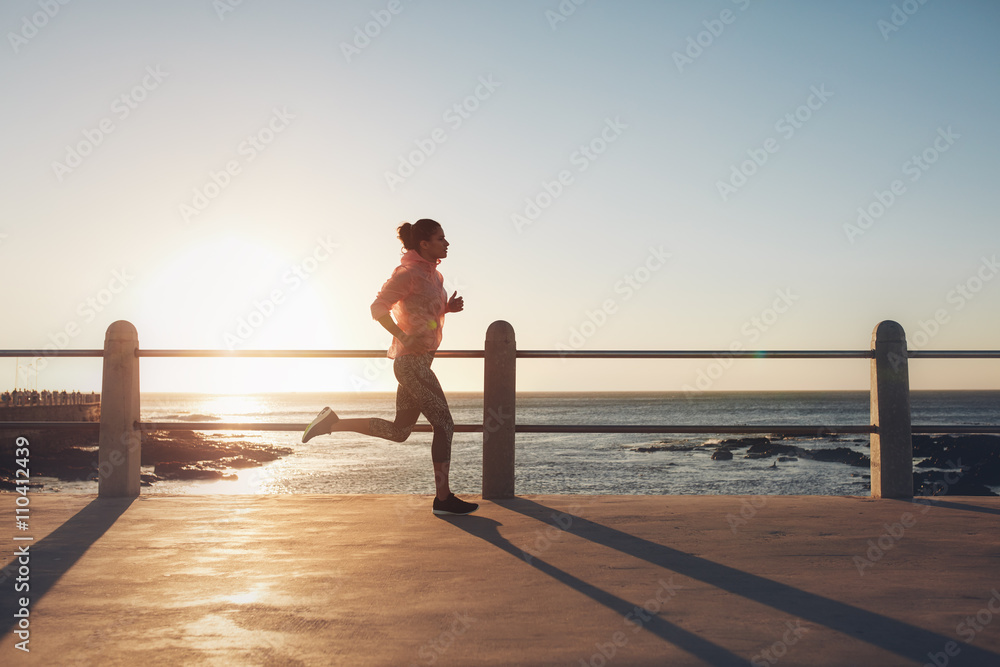 健康年轻的女人在海边的路上奔跑