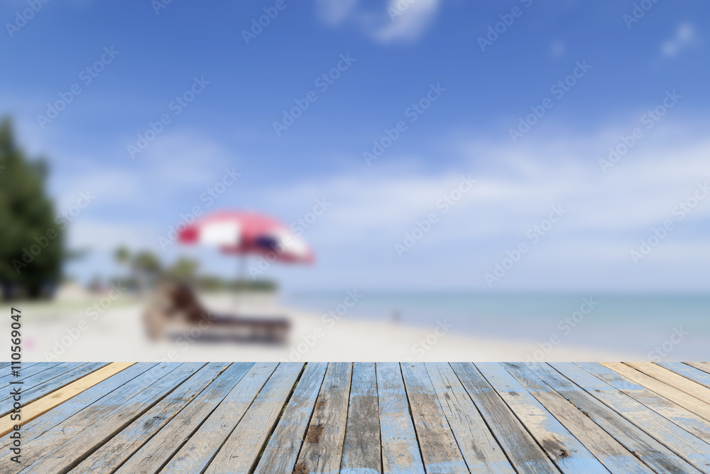 wooden floor with blur beach and blue sky  for background.