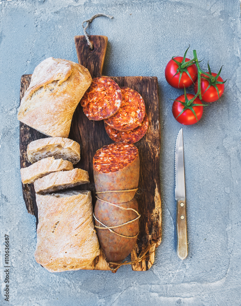 Wine snack set. Hungarian mangalica pork salami sausage, rustic bread and fresh tomatoes on dark woo
