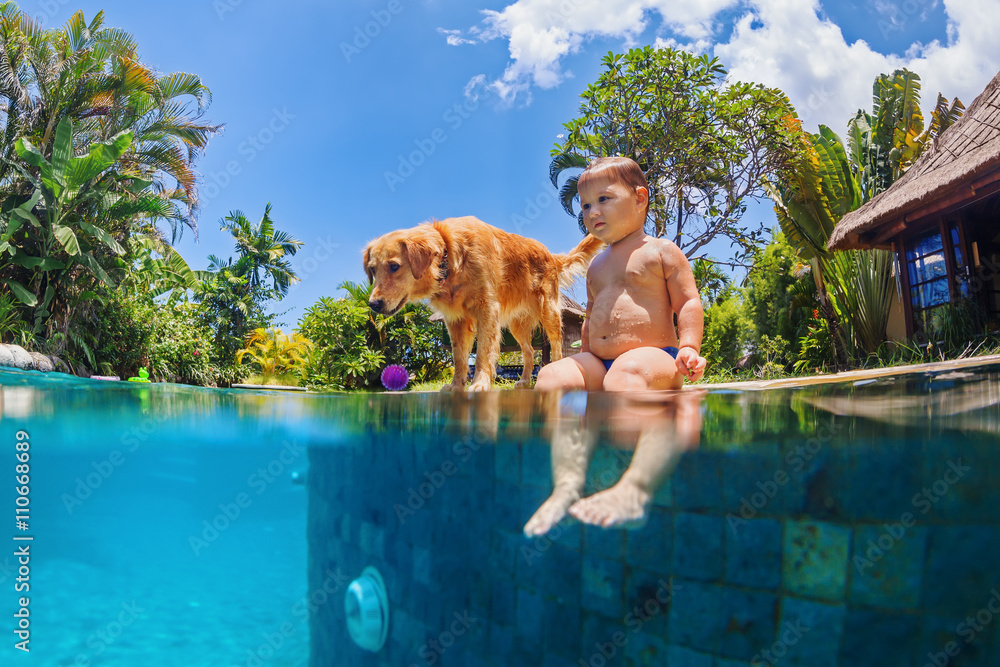 有趣的水下照片，小婴儿和狗在蓝色室外游泳池游泳。孩子们在游泳