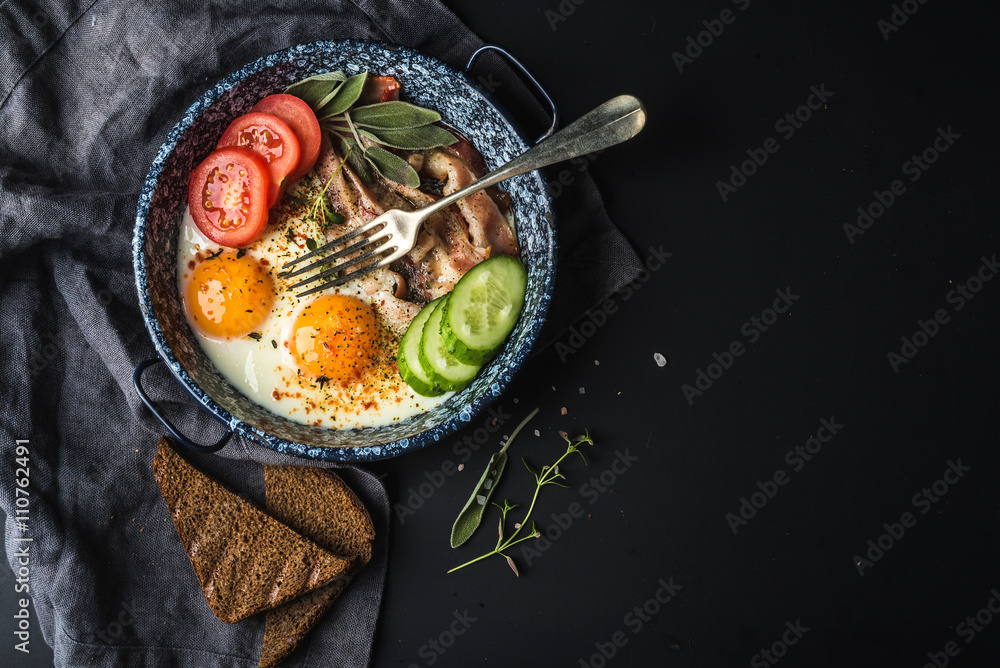 早餐套装。煎鸡蛋配培根、新鲜番茄、黄瓜、鼠尾草和面包，深色食用